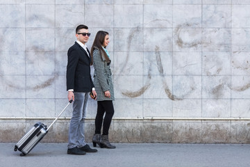 Young business couple with suitcase walking