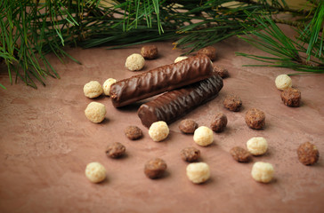 Obraz na płótnie Canvas chocolate on the brown surface with branches of pine needles