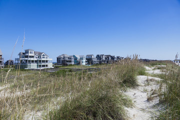 Fototapeta na wymiar Atlantic coast vacation rentals under blue sky with sand dunes in the foreground. Horizontal.