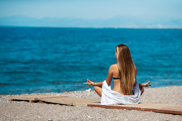 Fototapeta na wymiar woman in lotus pose meditating at beach 