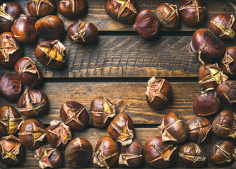 Close-up of roasted chestnuts over rustic wooden table background, top view, copy space, horizontal composition