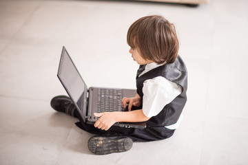 Little cute boy with laptop at home