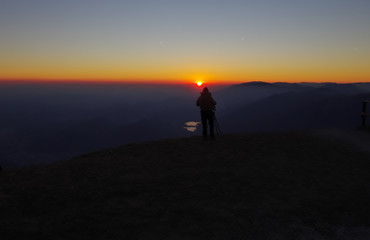 Photographer on the cliff above the lakes at sunset