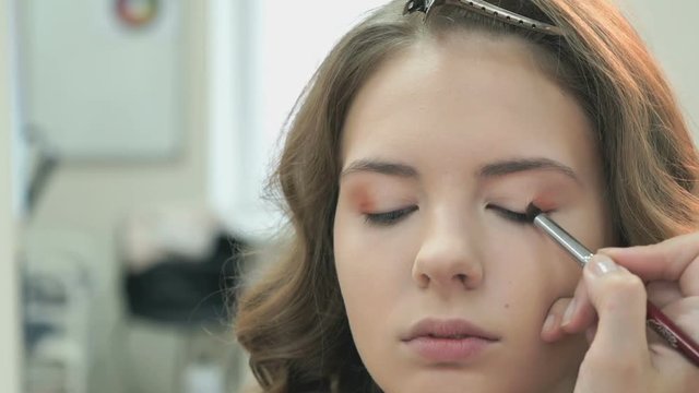 Beautiful model gets a professional makeup done by the professional makeup artist at the beauty salon