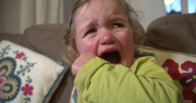 Toddler girl crying with mouth wide open and tears down her face