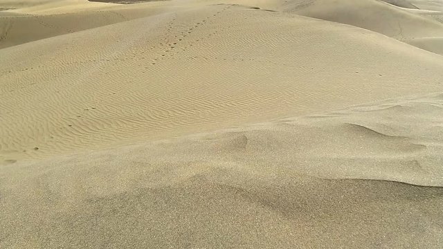 Wind blowing sand grains over sand dunes time lapse