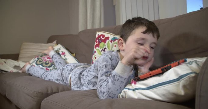 Cute boy in his pajamas watching a tablet computer