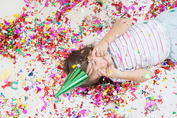 Young boy blows out confetti, isolated on white background