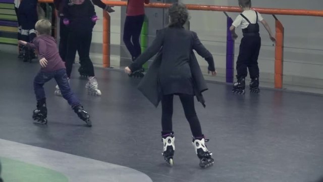 Teenagers and children ride on rollers at rollerdrome, slow motion