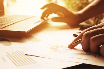 Businessman holding pen on charts and graph to find out the resu