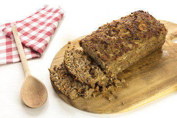 Freshly cooked and cut meatloaf on wooden board
