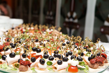a lot of snacks with skewers and sandwiches on buffet table