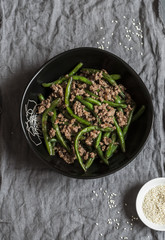 Pork and green beans stir fry on a dark table, top view