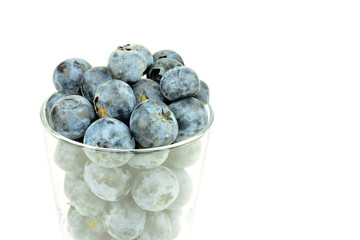 Heidelbeeren im Glas vor weißem Hintergrund mit Textfreiraum