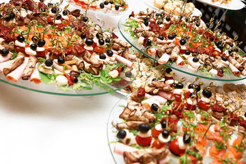 a lot of snacks with skewers and sandwiches on buffet table