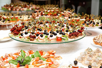 a lot of snacks with skewers and sandwiches on buffet table