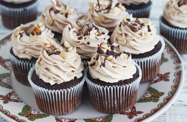 Chocolate cupcake with mousse cream icing on grunge white wooden background copy space