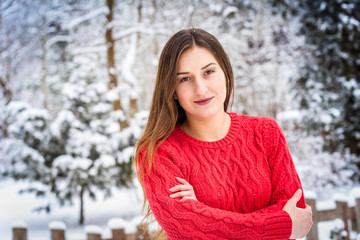 Winter. Girl in red pullover on snow background smiling
