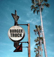 aged and worn vintage photo of burger truck sign with palm trees 