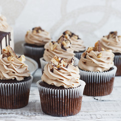 Chocolate cupcake with  mousse cream icing on grunge white wooden background  copy space