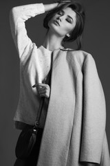 high fashion portrait of elegant woman in beige coat, blue jeans and knitted pullover. Studio shot....