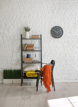 black bookshelf with black chair and black clock with white brick wall interior style