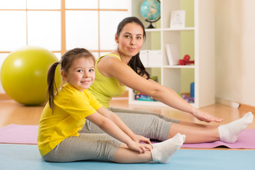Fototapeta na wymiar Child girl and her mother doing gym exercise at home