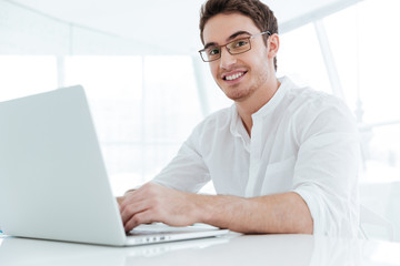 Happy young man using laptop computer.