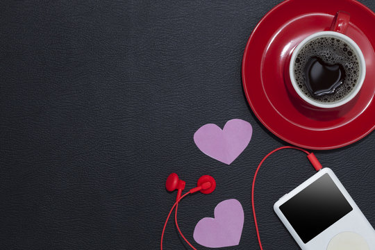 red coffee cup with music player and red earphone on black leath