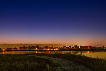 Fototapeta premium A path at night overlooking the San Francisco Bay wetlands. Palo Alto airport lights at night.
