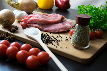 Fresh raw meat steak with spice and vegetables on wood surface