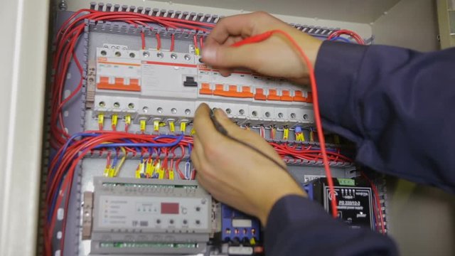 Electrician working with circuit breaker, tester, multimeter at a fuse box. HD.
