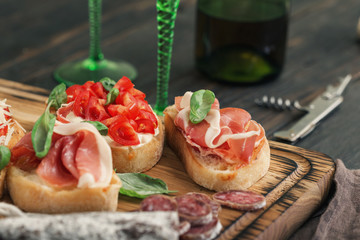 Set of small sandwiches with prosciutto, tomatoes, fresh basil