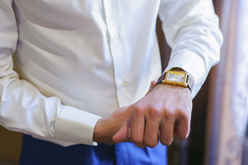 A man in a white shirt straightens his cufflinks