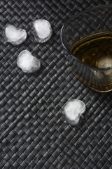 One glass of brandy with ice on black leather background