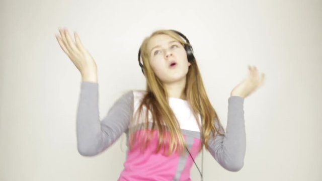 young girl listening music on headphones and funy dancing