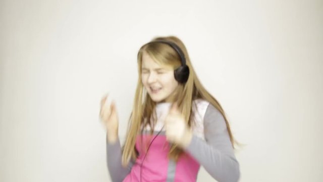 young girl listening music on headphones and funy dancing