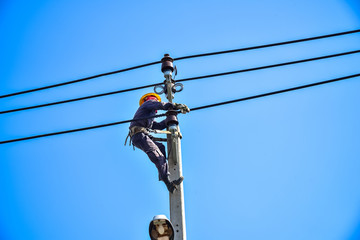 Electrician perform maintenance on the transmission towers with use of claws- manholes and belt