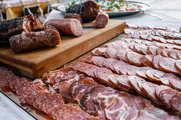 Sliced sausages and other kinds of smoked meat lie on mirror tra