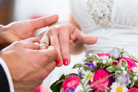 Bräutigam steck Braut bei Hochzeit Ring an