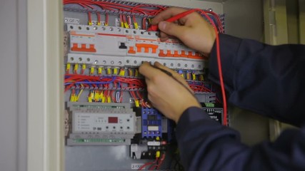 electrician hands checking circuit breakers in electrical fuse box. HD.