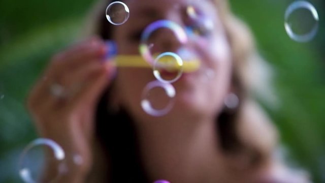 Young pretty woman blowing bubbles