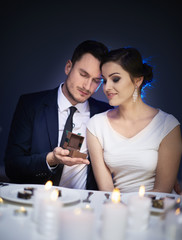 Man surprising woman with engagement ring at restaurant table