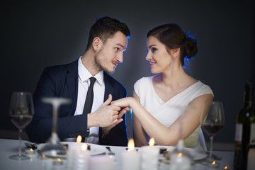 Man holding girlfriends hand at dinner