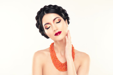 Gorgeous Brunette Woman. Portrait of Beautiful Model with Perfect Bright Make up, Red Lips, Orange Jewelry. Sexy Lady Makeup for Party. Girl with Elegant Braided Hairdo, Colorful Make Up and Necklace