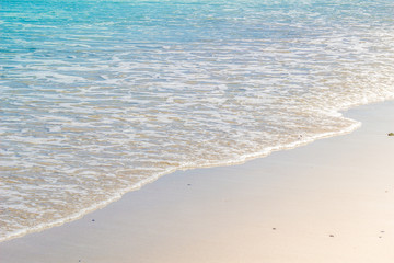Fototapeta na wymiar Soft wave of blue ocean on wet sandy beach. Background