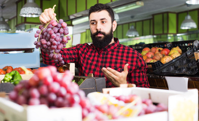 Man seller choosing  grapes in grocery shop