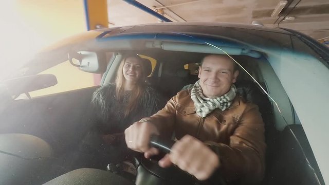 View of a man and a woman smiling sitting in a car. View through the window of a car. Camera attached to front bumper