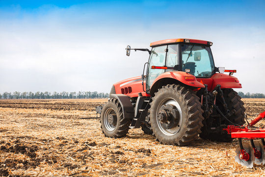 Fototapeta Red tractor in the field on a bright sunny day.