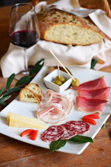Mediterranean charcuterie snacks, antipasto with bread, wine, salumi, nuts, olives and pickles